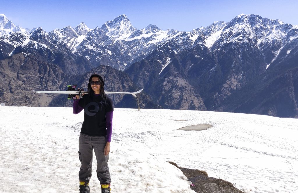 A girl wearing skiing gear posing at the backdrop of Himalayas in Auli, skiing in auli